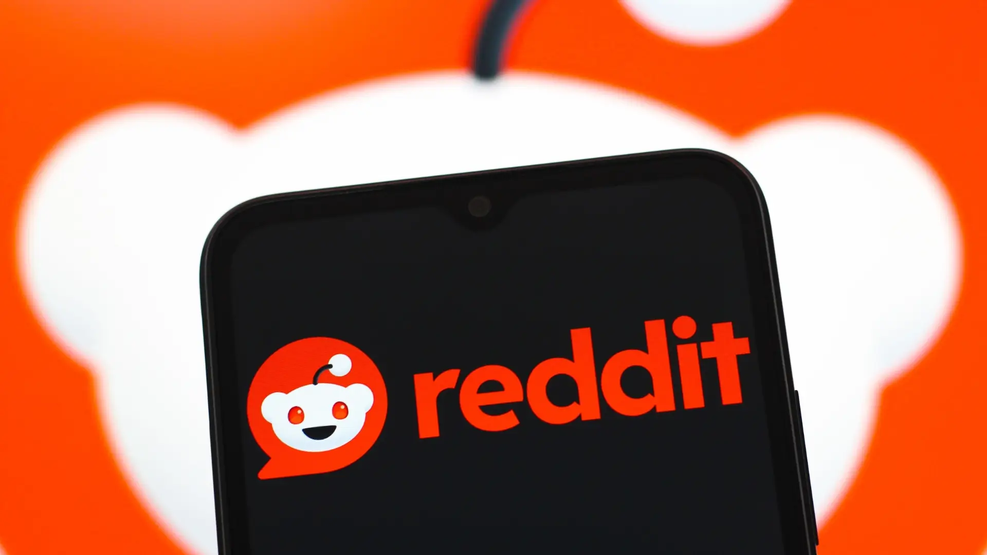 Reddit app logo on smartphone, highlighting GEO strategy using Reddit communities for AI content visibility.