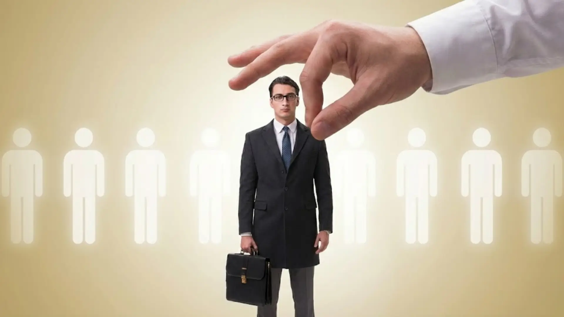 A professional man in a dark suit holding a briefcase stands in front of a row of white human icons on a beige background, while a giant hand reaches down to pick him, symbolizing recruitment, hiring, or selection.